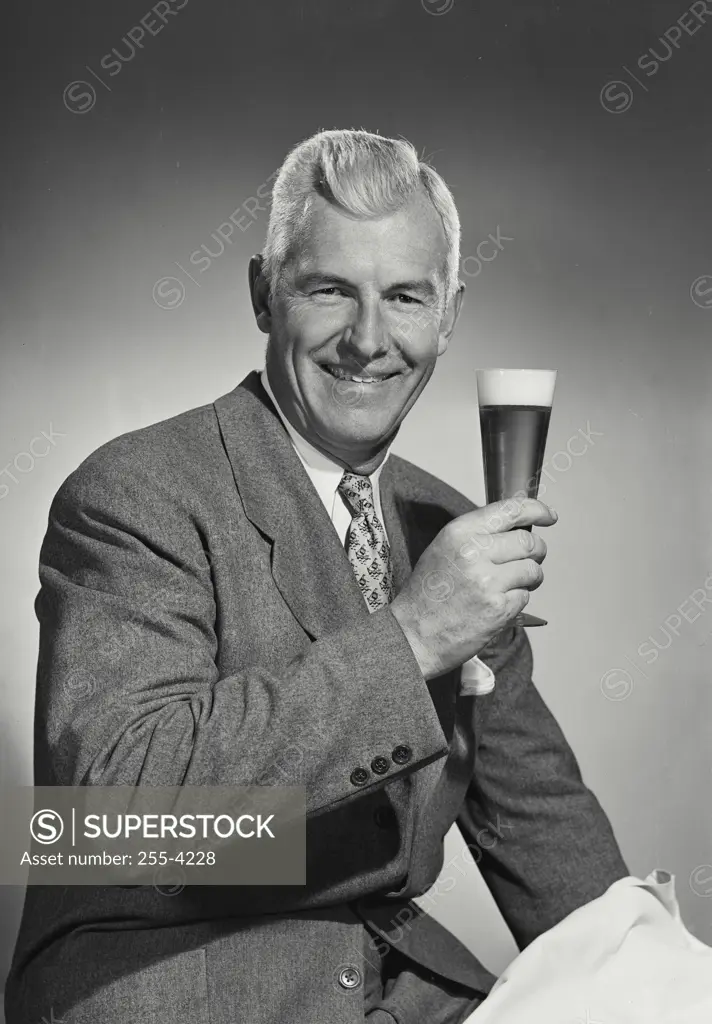 Vintage Photograph. Older man in suit and tie holding glass of beer. Frame 1