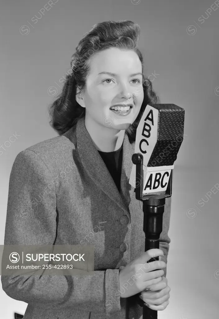 Studio portrait of female reporter speaking into microphone 