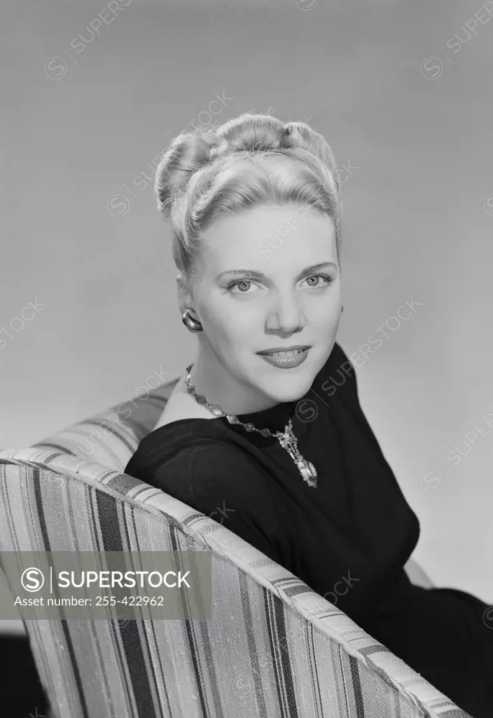 Studio portrait of young woman sitting in chair