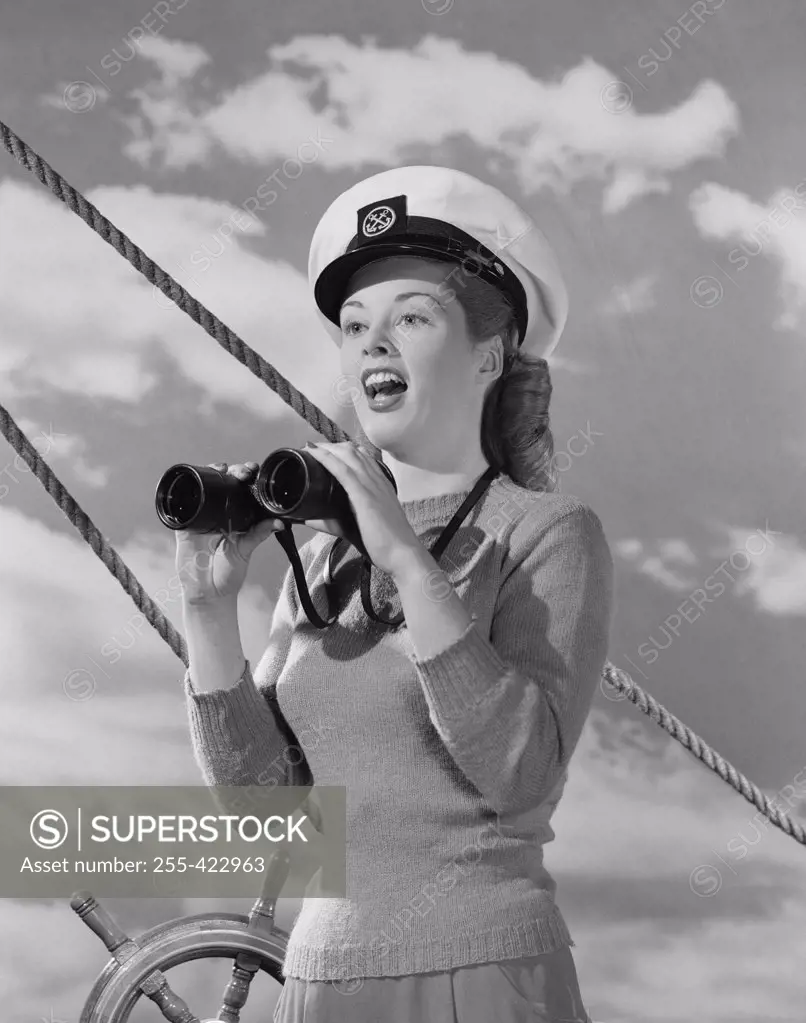 Female sailor holding binoculars at helm