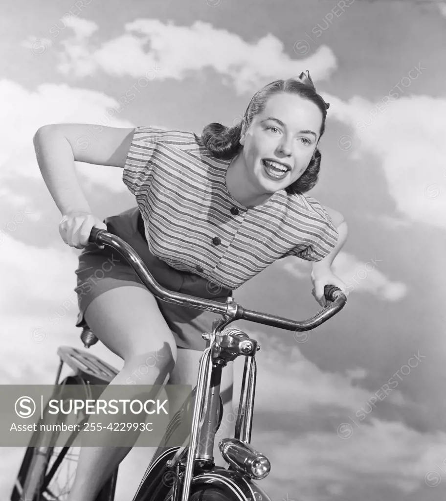 Young woman riding bicycle against cloudy sky