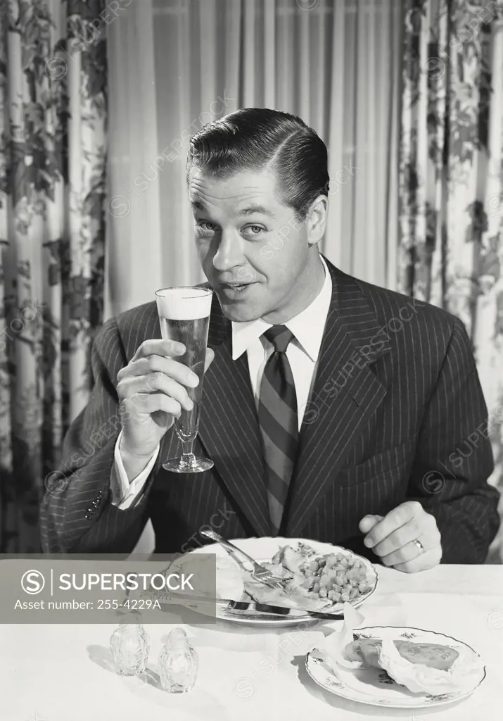 man at dinner raising glass.