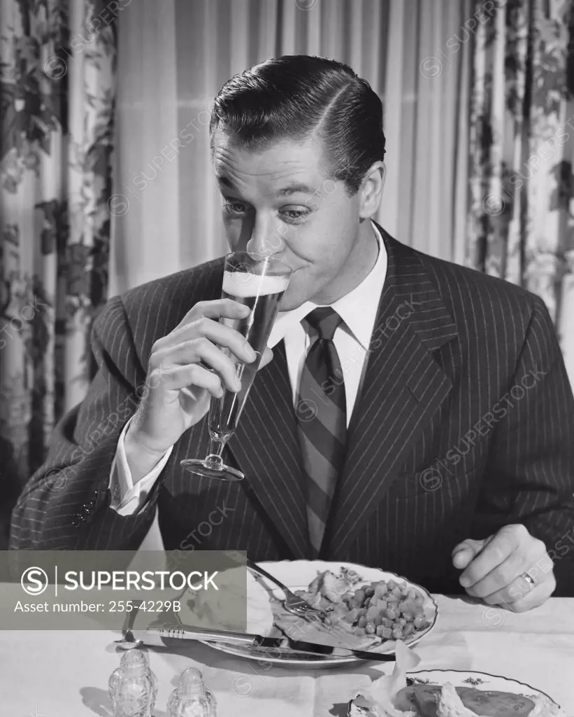 Mid adult man sitting at table drinking beer