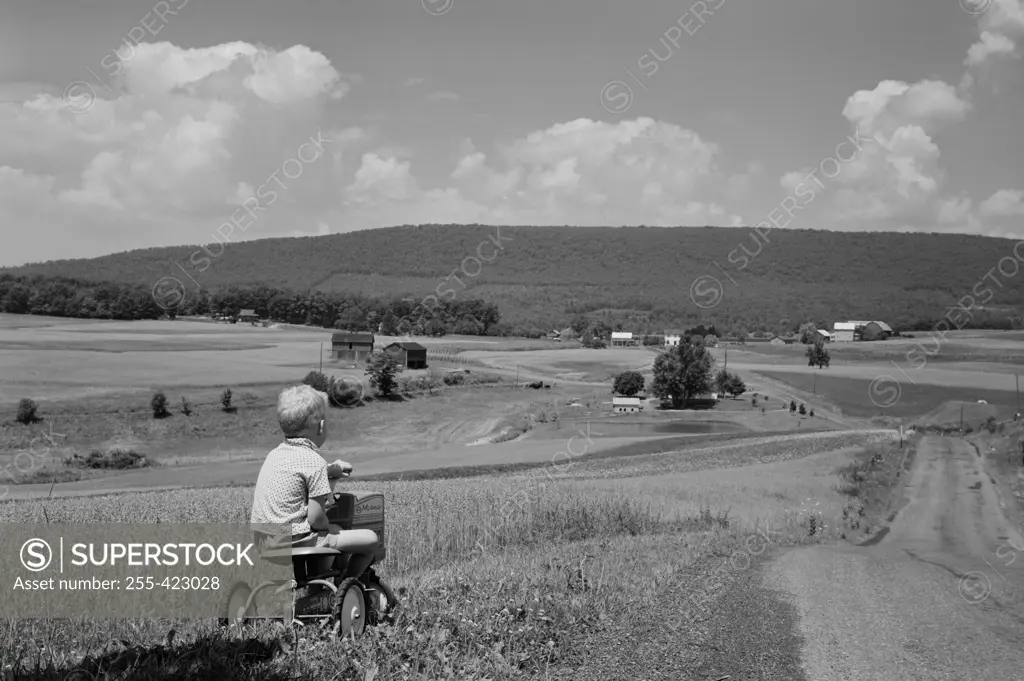 Boy riding tricycle in rural scenery