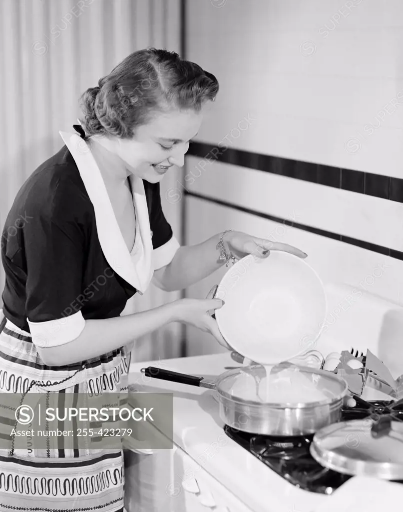 Happy young woman making omelet