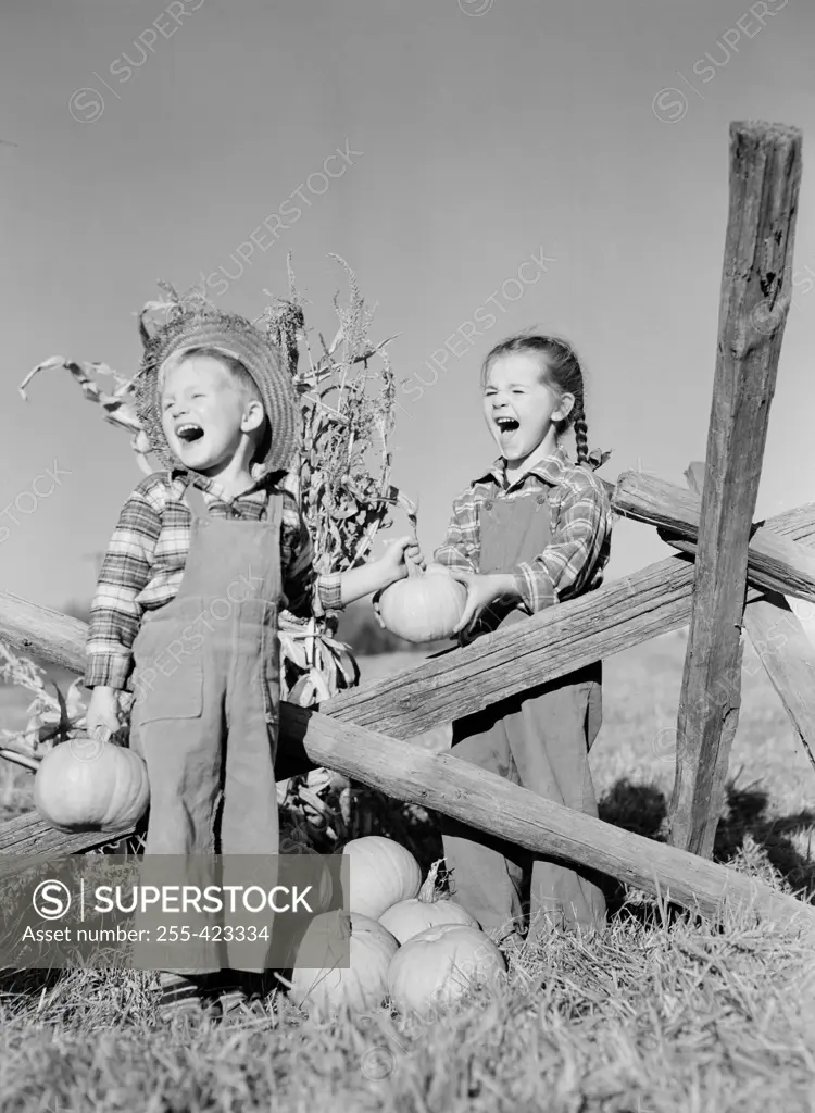 Boy and girl with pumpkins on farm