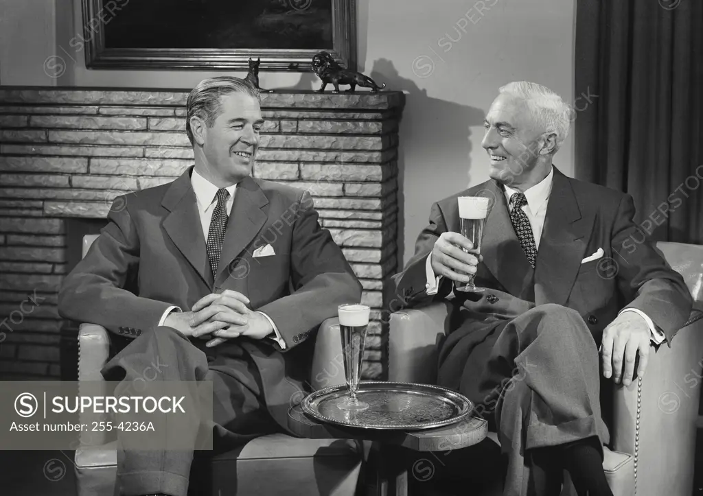 Vintage Photograph. Men in suits sitting in chairs talking with beers