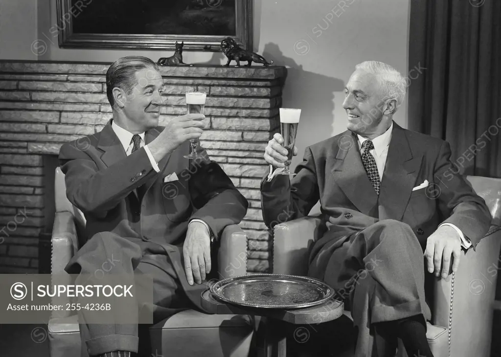 Vintage Photograph. Men in suits sitting in chairs talking with beers raised
