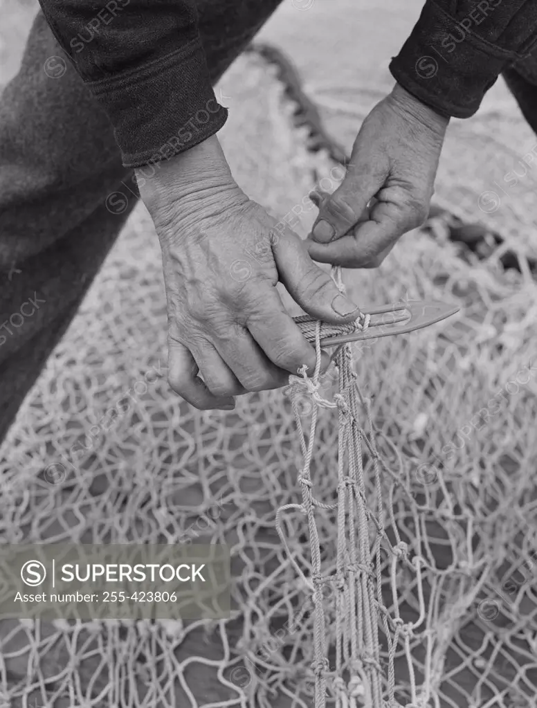 USA,  Washington, Seattle, close up of man's hands mending fishing net