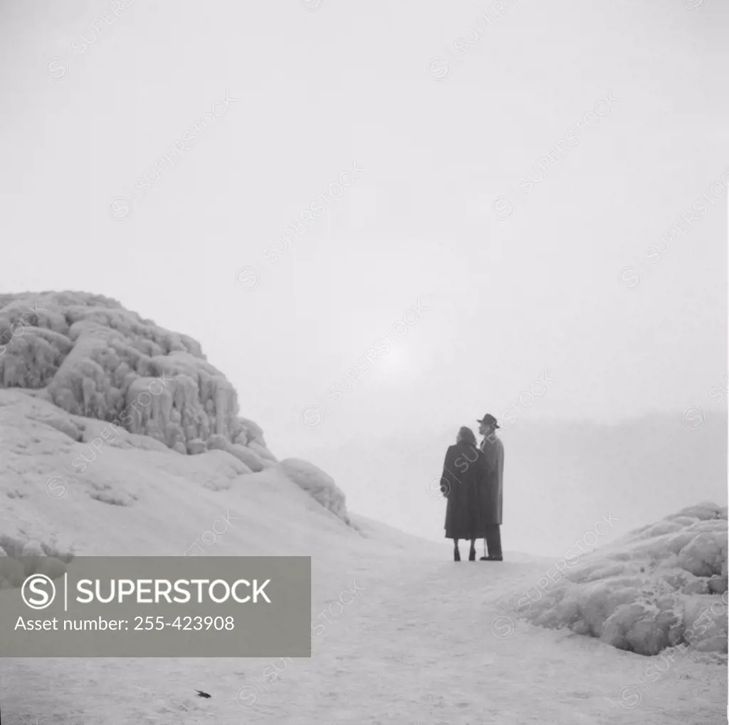 Canada, Ontario, Honeymoon couple enraptured by winter sunset at Niagra Falls