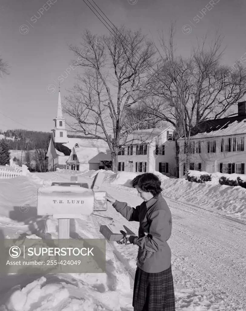 USA, Vermont, Waterford, woman taking Christmas mail from rural mail box