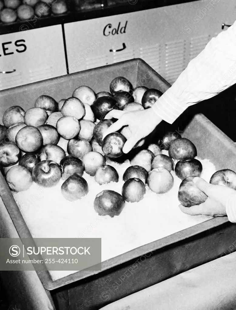 Hand taking apples from ice display box