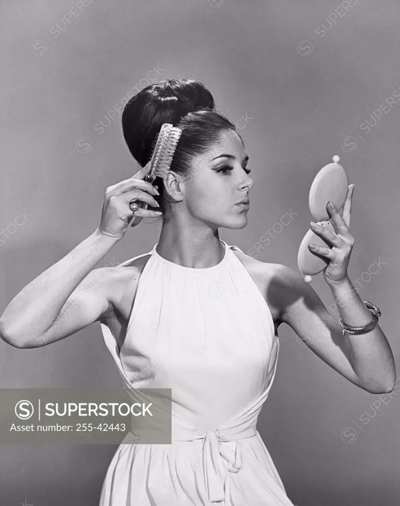 Young woman with hairbun brushing her hair