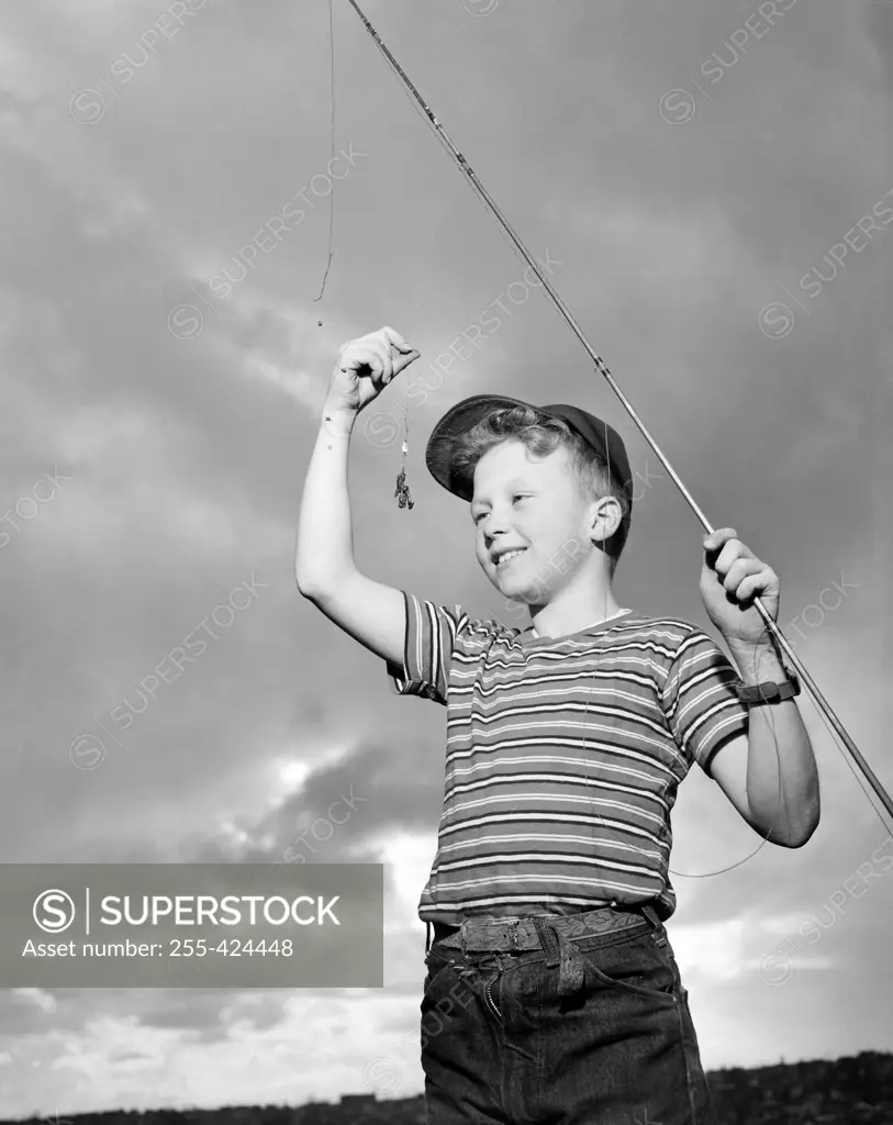 Boy holding fishing rod and looking at fishing bait