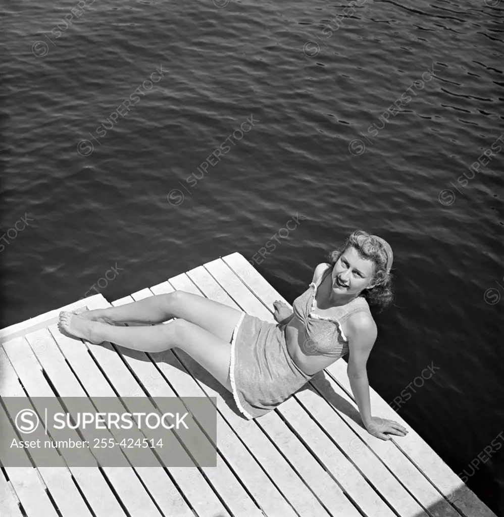 Young woman wearing bikini sitting on pier