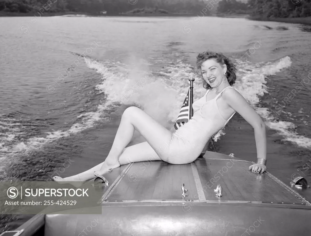Young woman in bikini sitting on speed boat