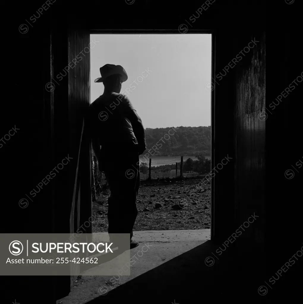 Cowboy standing in open doors and looking away