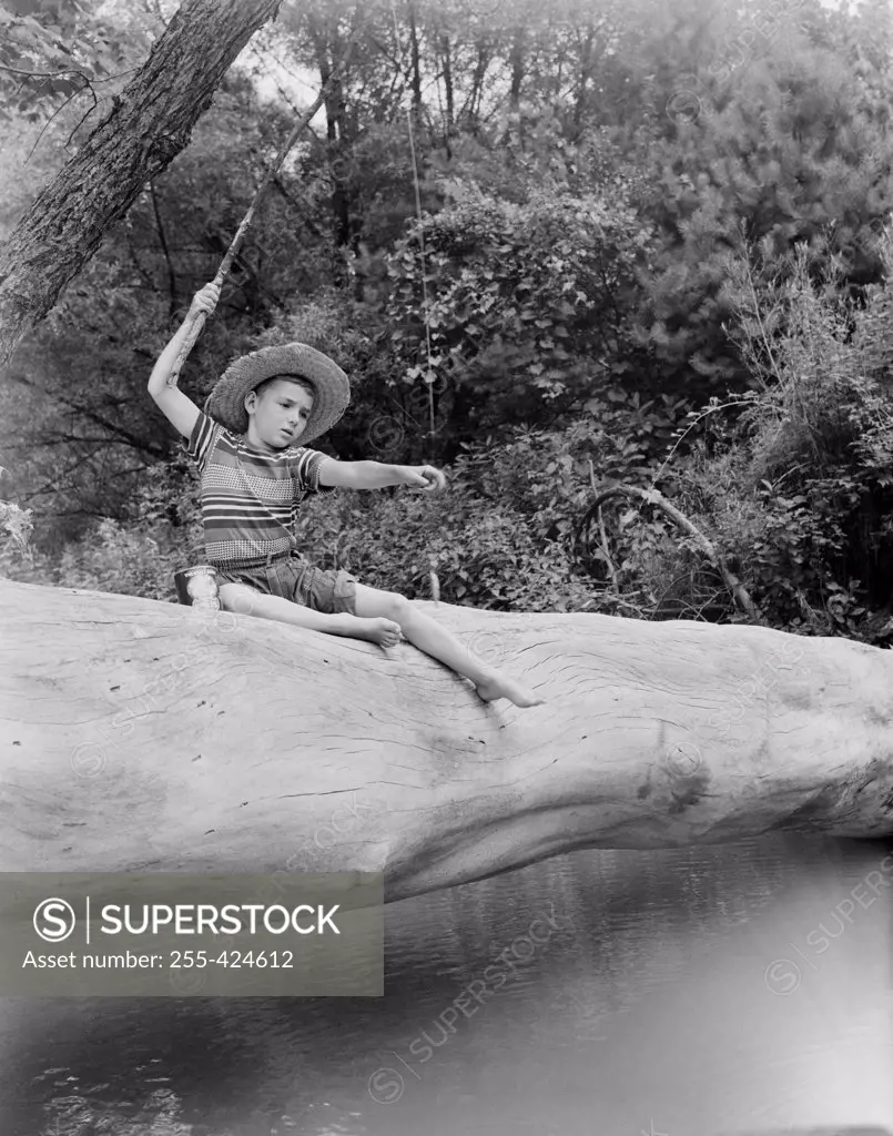 Boy sitting on tree trunk and fishing