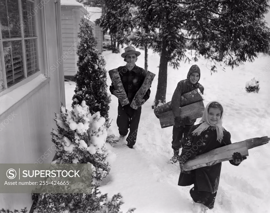 Children with father carrying wood logs in winter