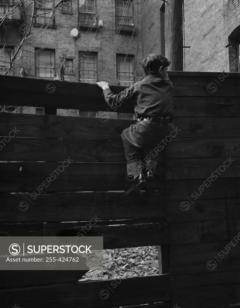 Rear view of boy climbing over fence