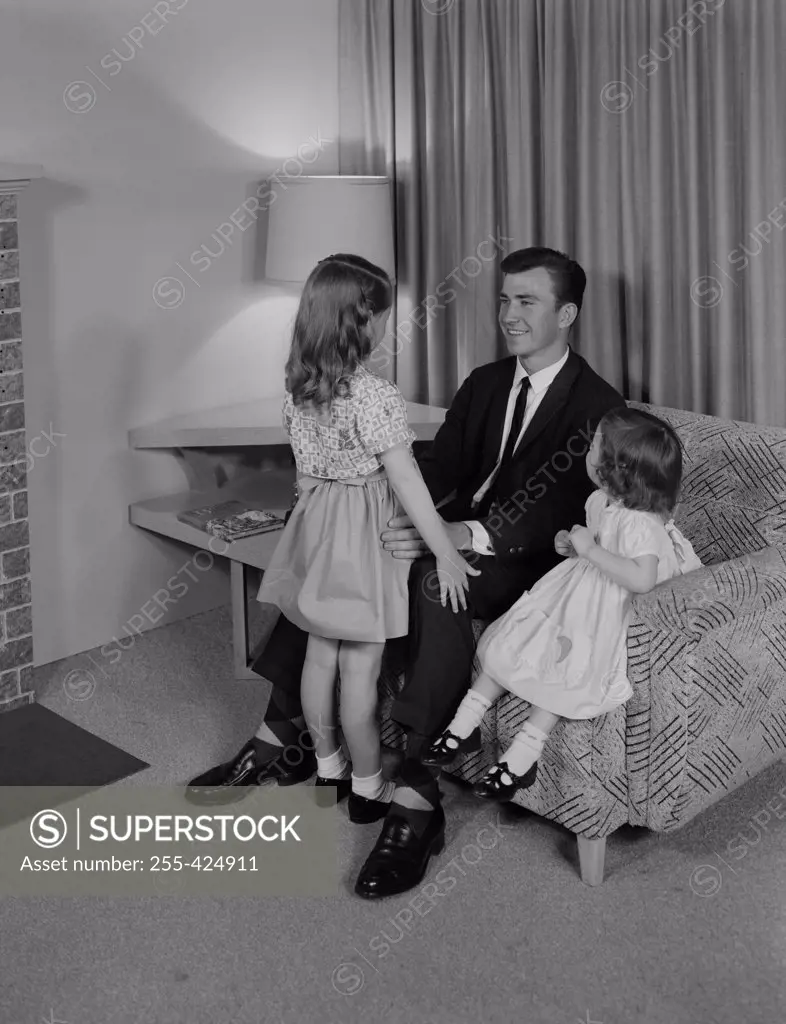 Father relaxing with daughters in living room