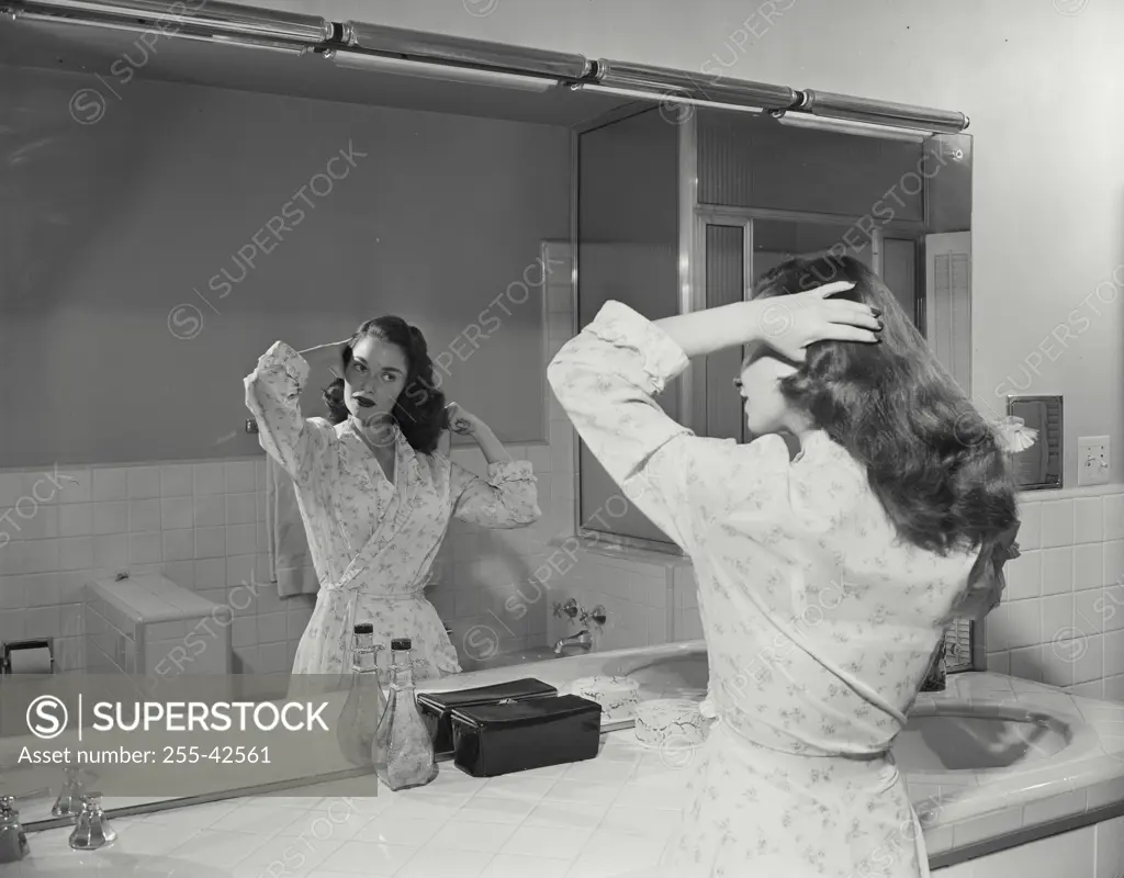 Vintage Photograph. Woman wearing bathrobe getting ready in bathroom mirror brushing hair
