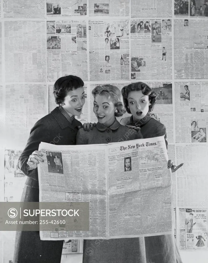 Three young women reading a newspaper