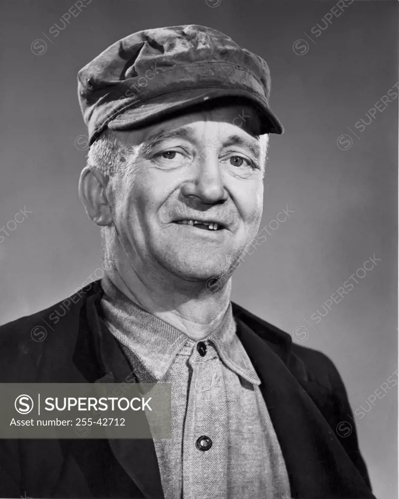 Vintage Photograph. Elderly caucasian man with chipped front teeth wearing dirty jacket and hat