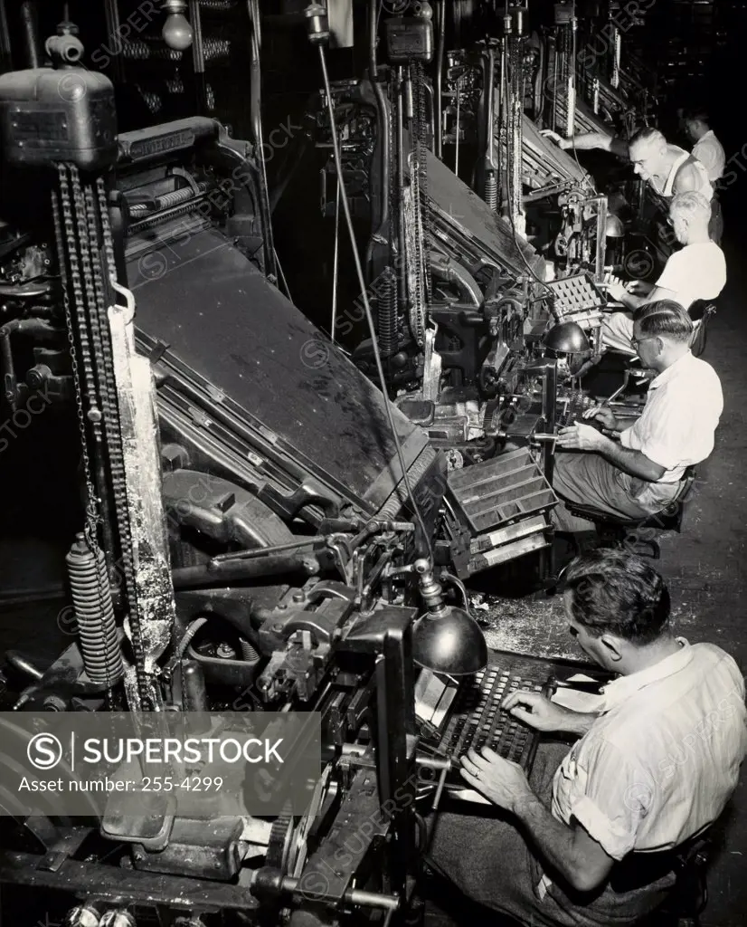 High angle view of a group of male workers operating linotype machines, New York World Telegraph