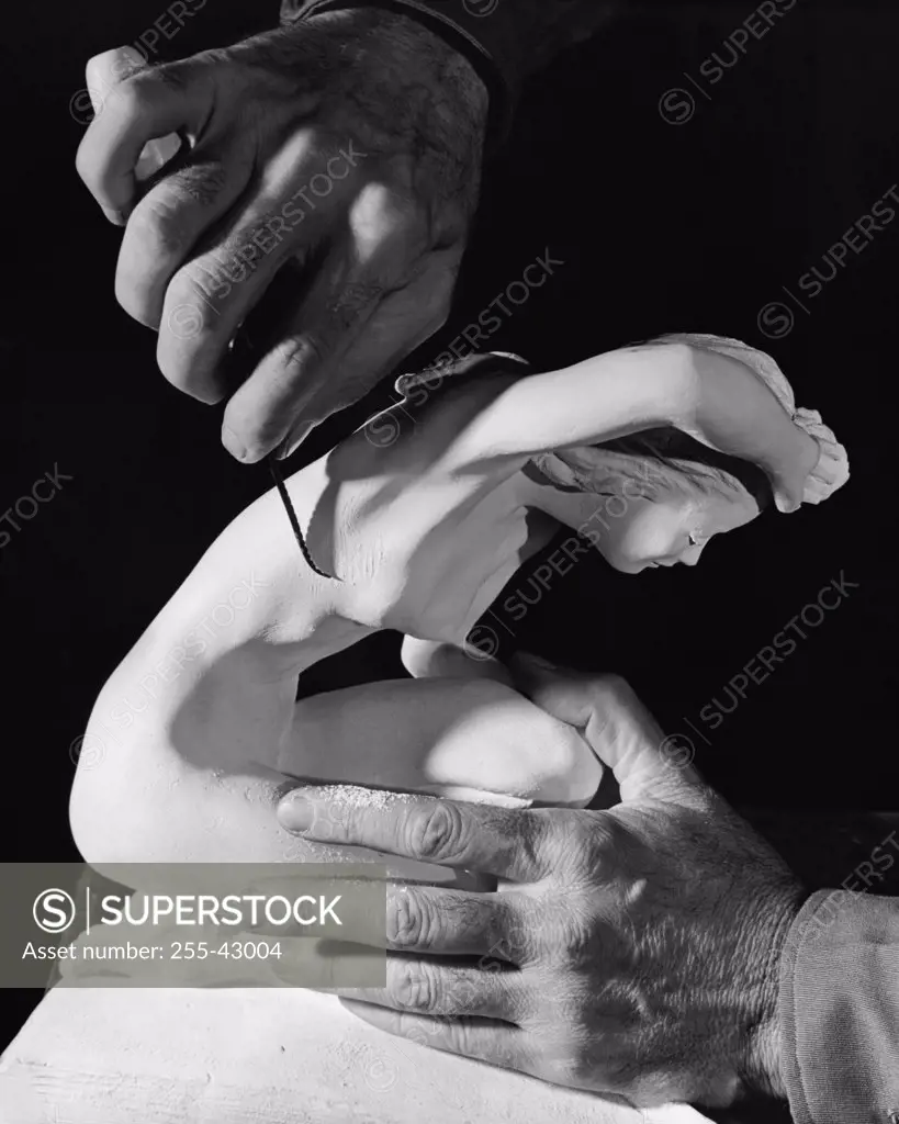 Close-up of a person's hands carving a statue