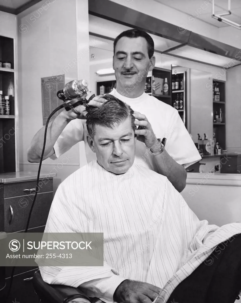 Hairdresser massaging hair of a mid adult man
