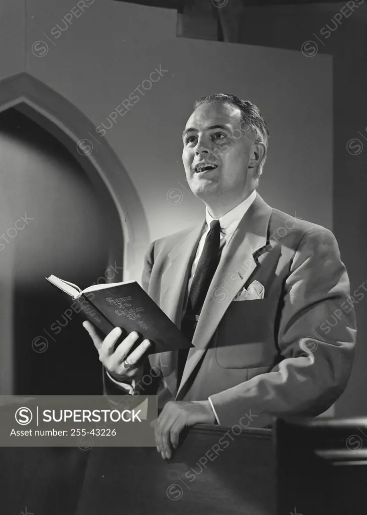 Man in church happily singing from Hymnal book