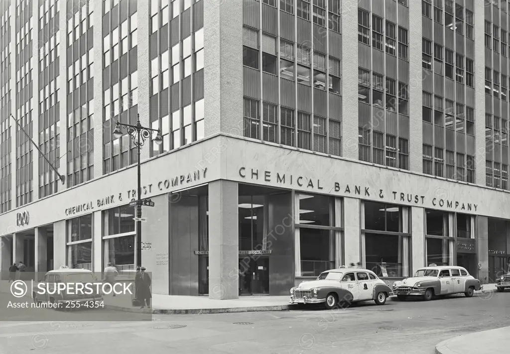 Vintage photograph. Exterior of Chemical Bank and Trust Company on 100 Park Avenue, New York with man standing on corner and taxis parked out front