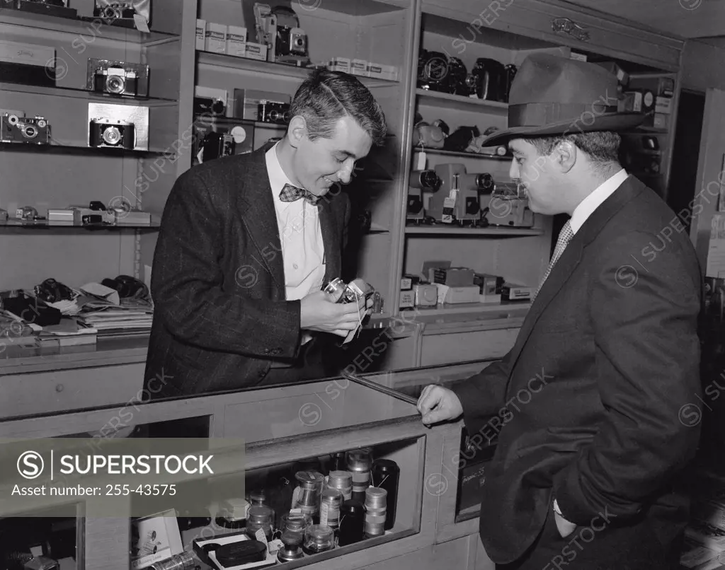 Salesman showing a camera to a customer in a store