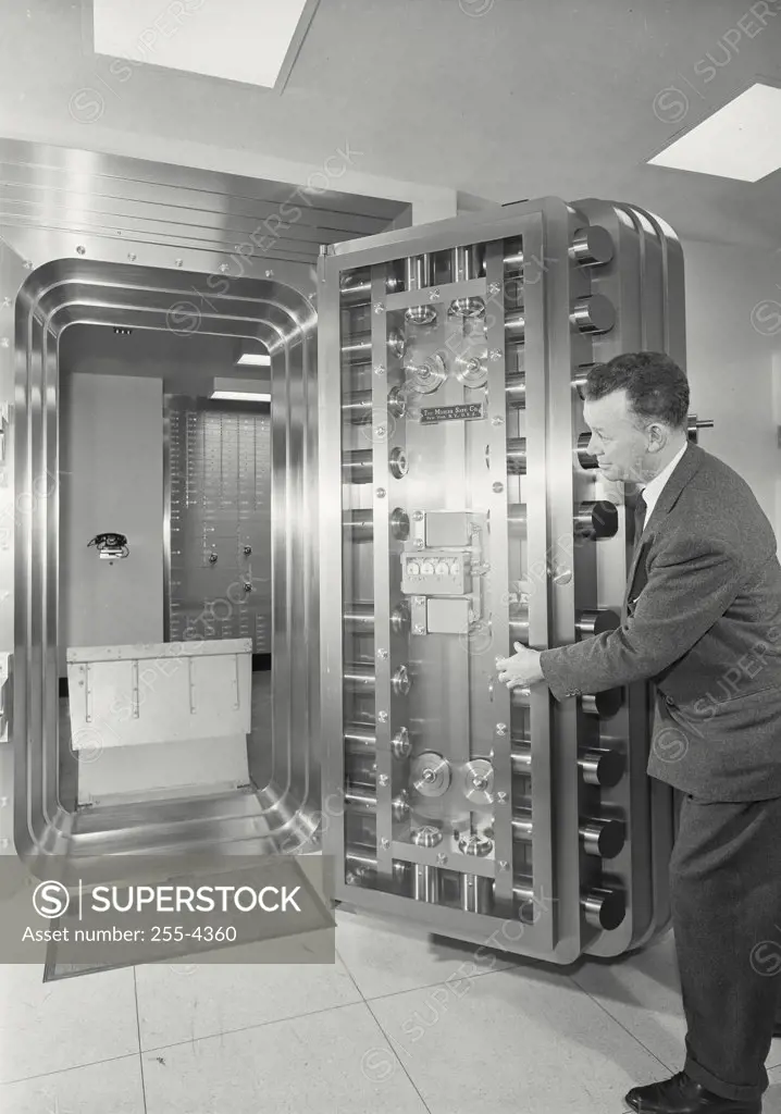 Vintage photograph. Side profile of a mature man opening Door of vault at Chemical Bank and Trust