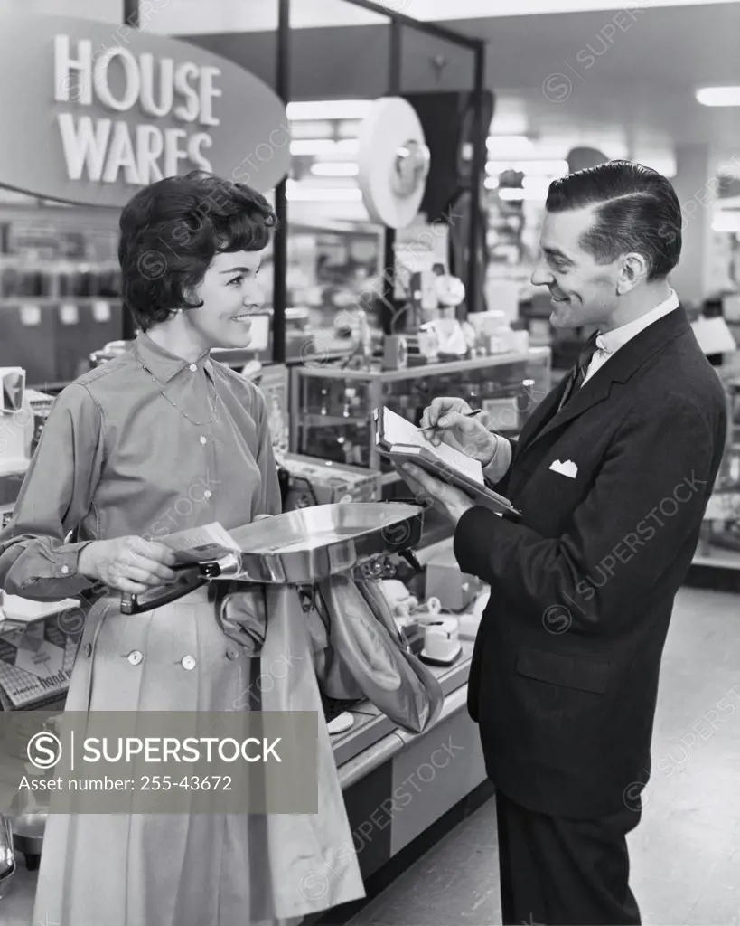 Side profile of salesman and female customer smiling in store