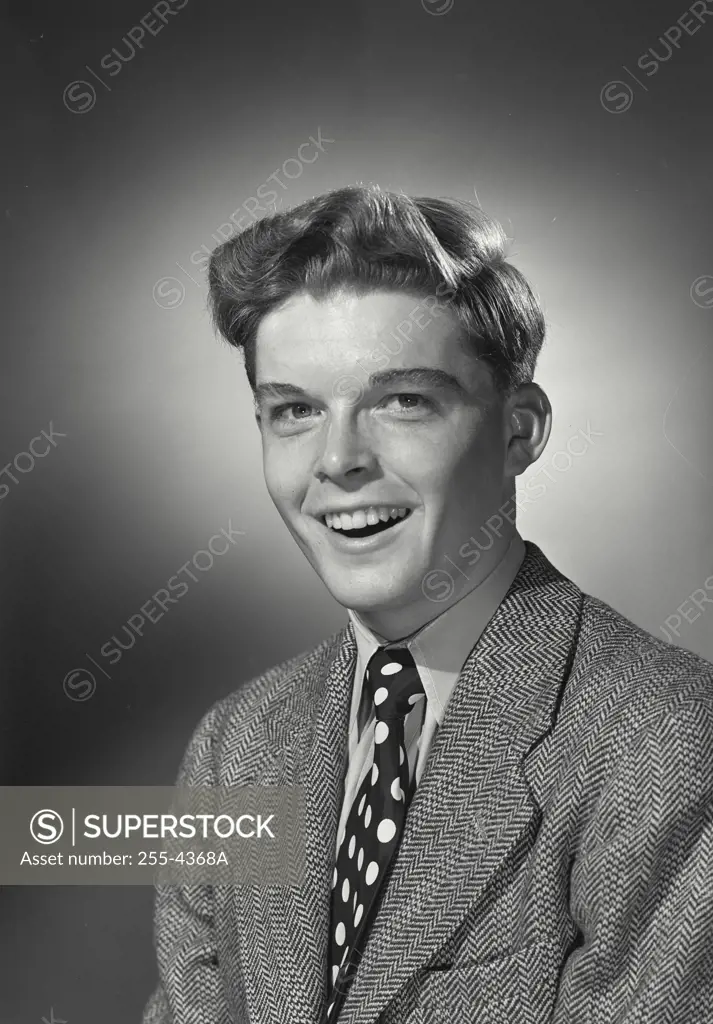 Vintage Photograph. Teenage boy in blazer and polka dot tie with comical smile expression
