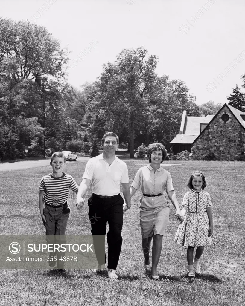 Portrait of parents and their children walking on a lawn