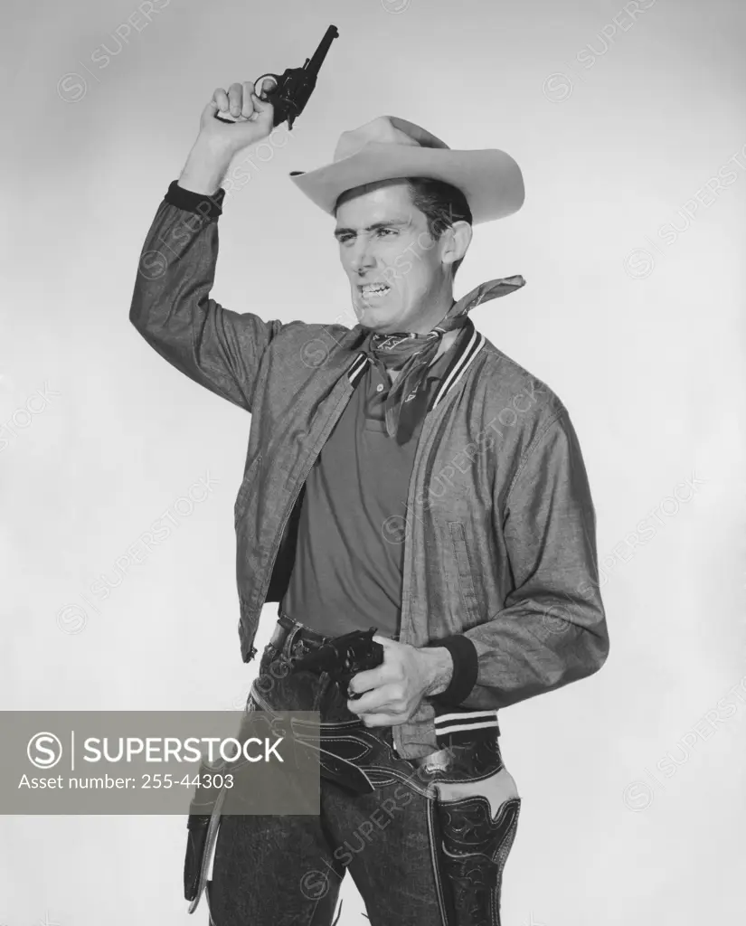 Portrait of cowboy shooting into the air and pointing handgun