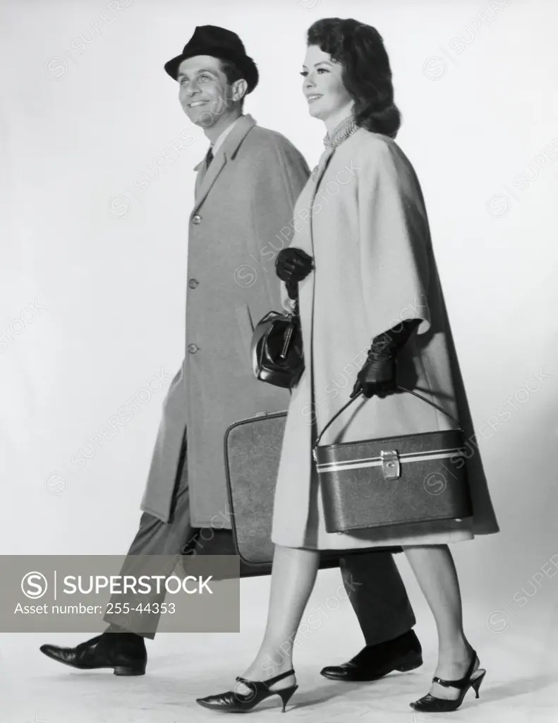 Side profile of a mid adult couple walking with luggage