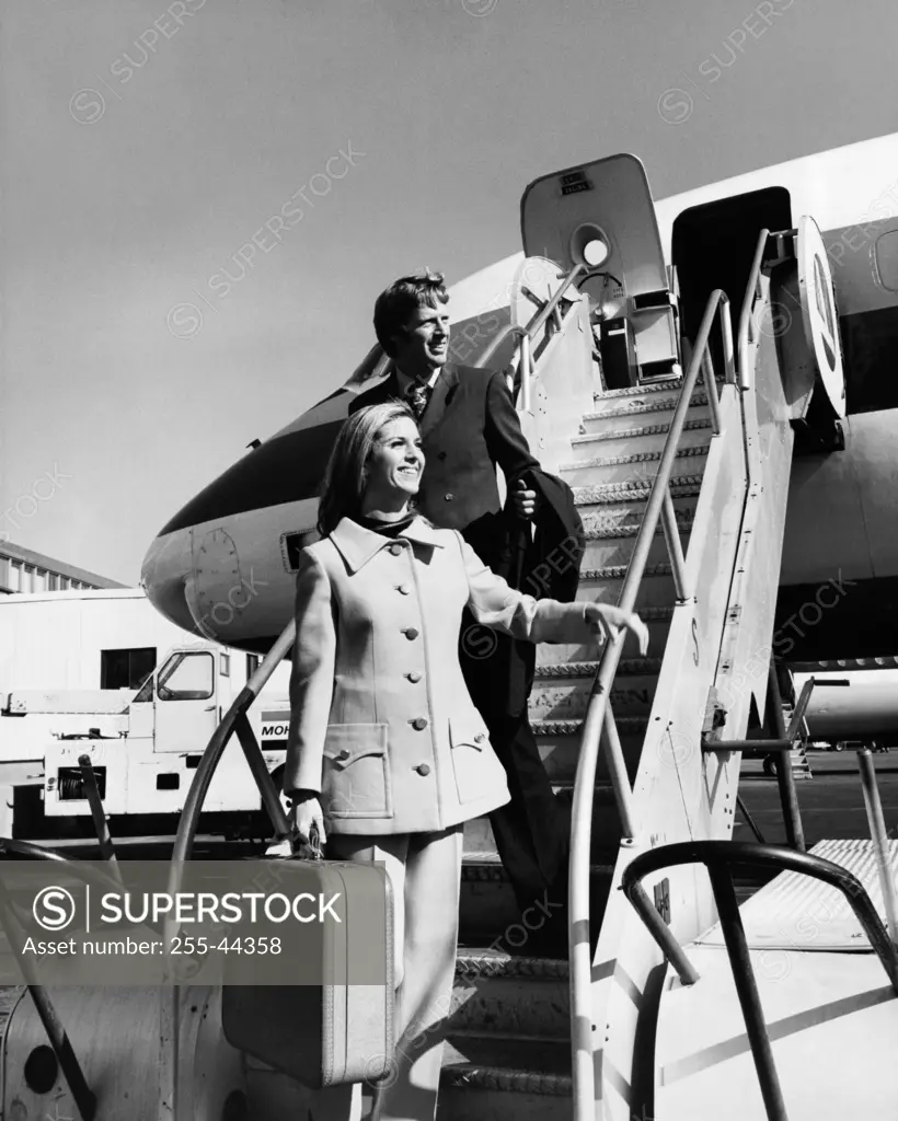 Young woman with a young man standing on a staircase of an airplane