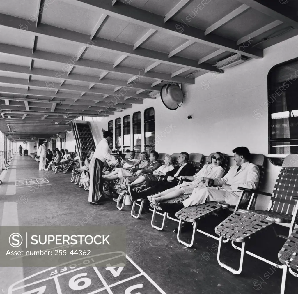 Tourists reclining on lawn chairs on a cruise ship