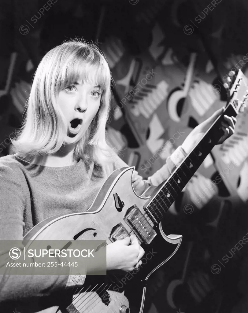 Portrait of a young woman playing an electric guitar and singing