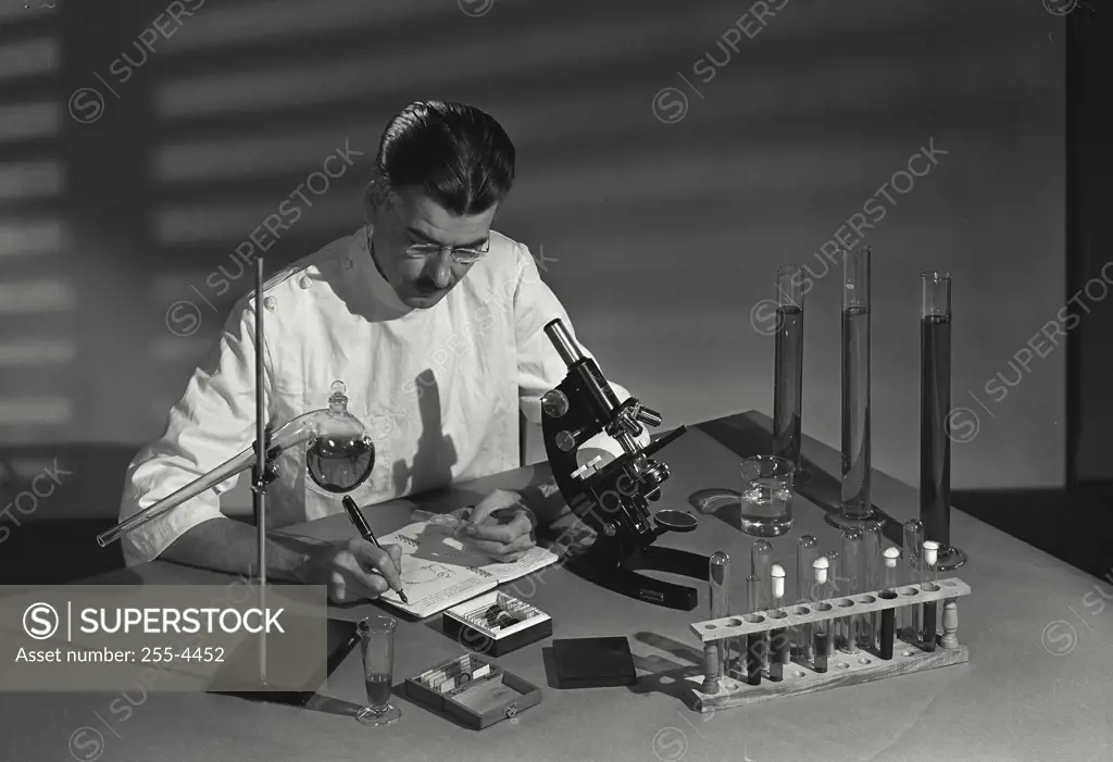 Vintage Photograph. Male researcher writing in a diary in a laboratory