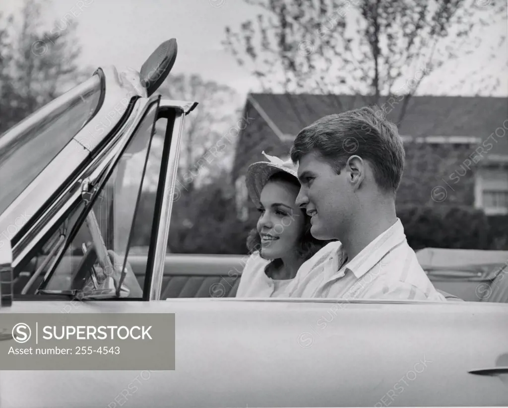 Side profile of young couple sitting in convertible car