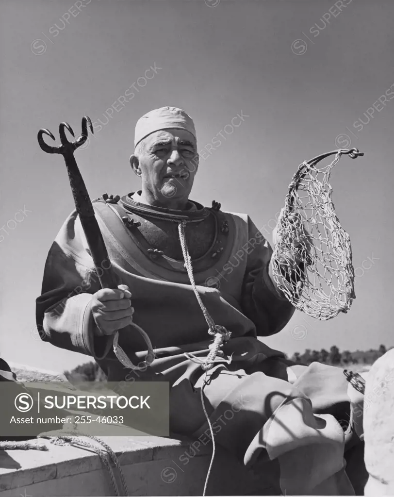 Sponge diver holding hook and fishing net - SuperStock