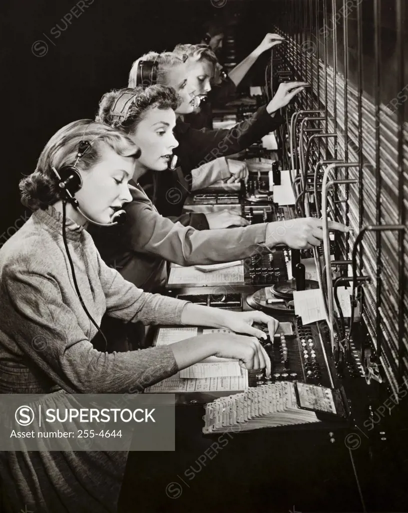 Side profile of a group of telephone operators operating switchboards