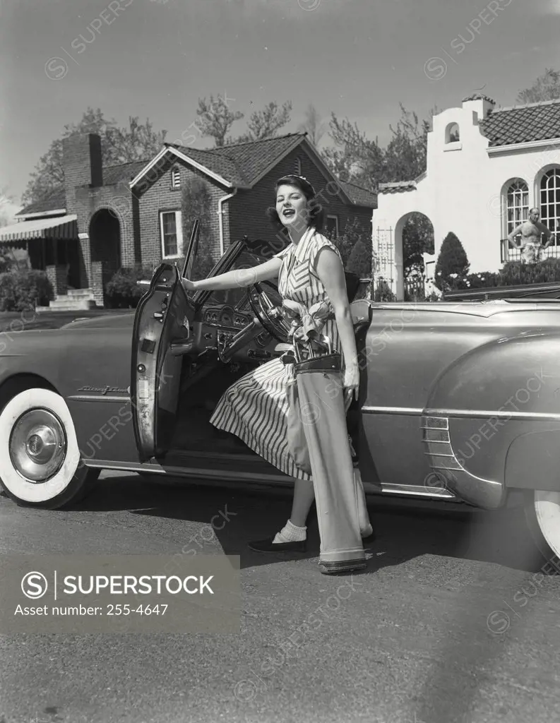 Vintage photograph. Woman with golf club case in front of convertible car