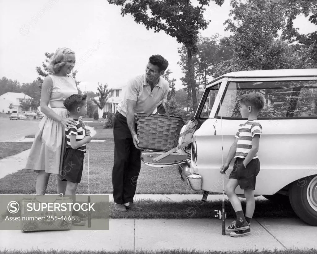 Parent and children loading luggage into car