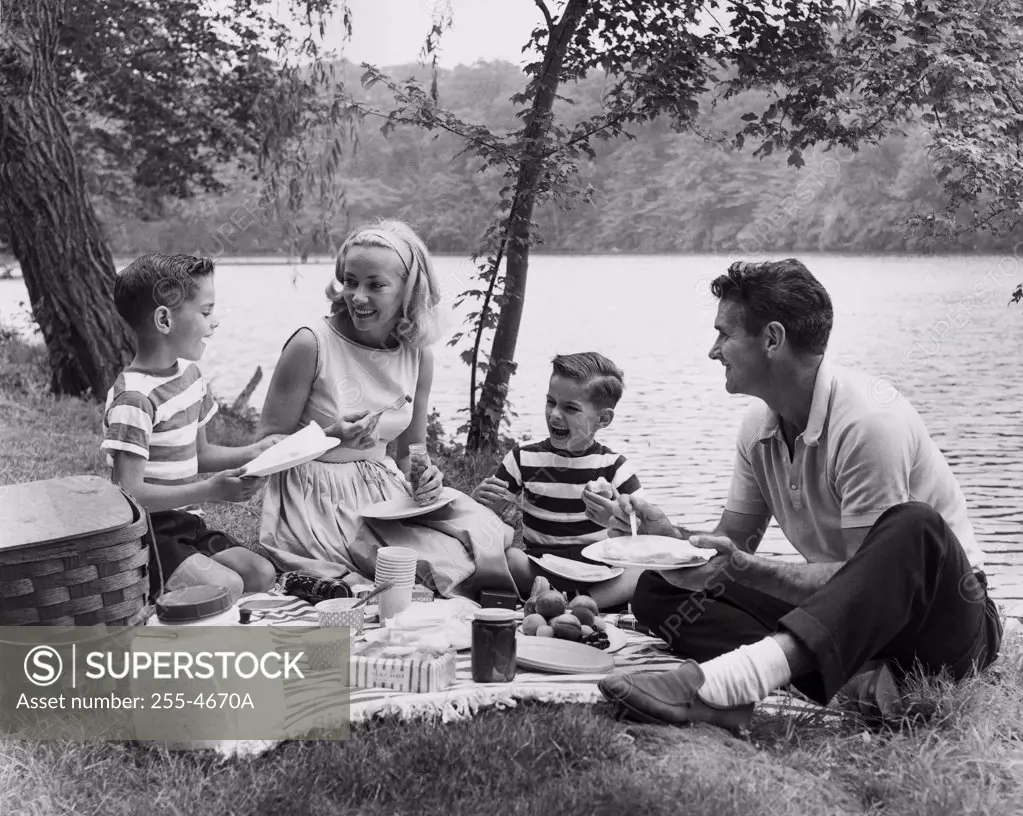 Parents and children having picnic near lake